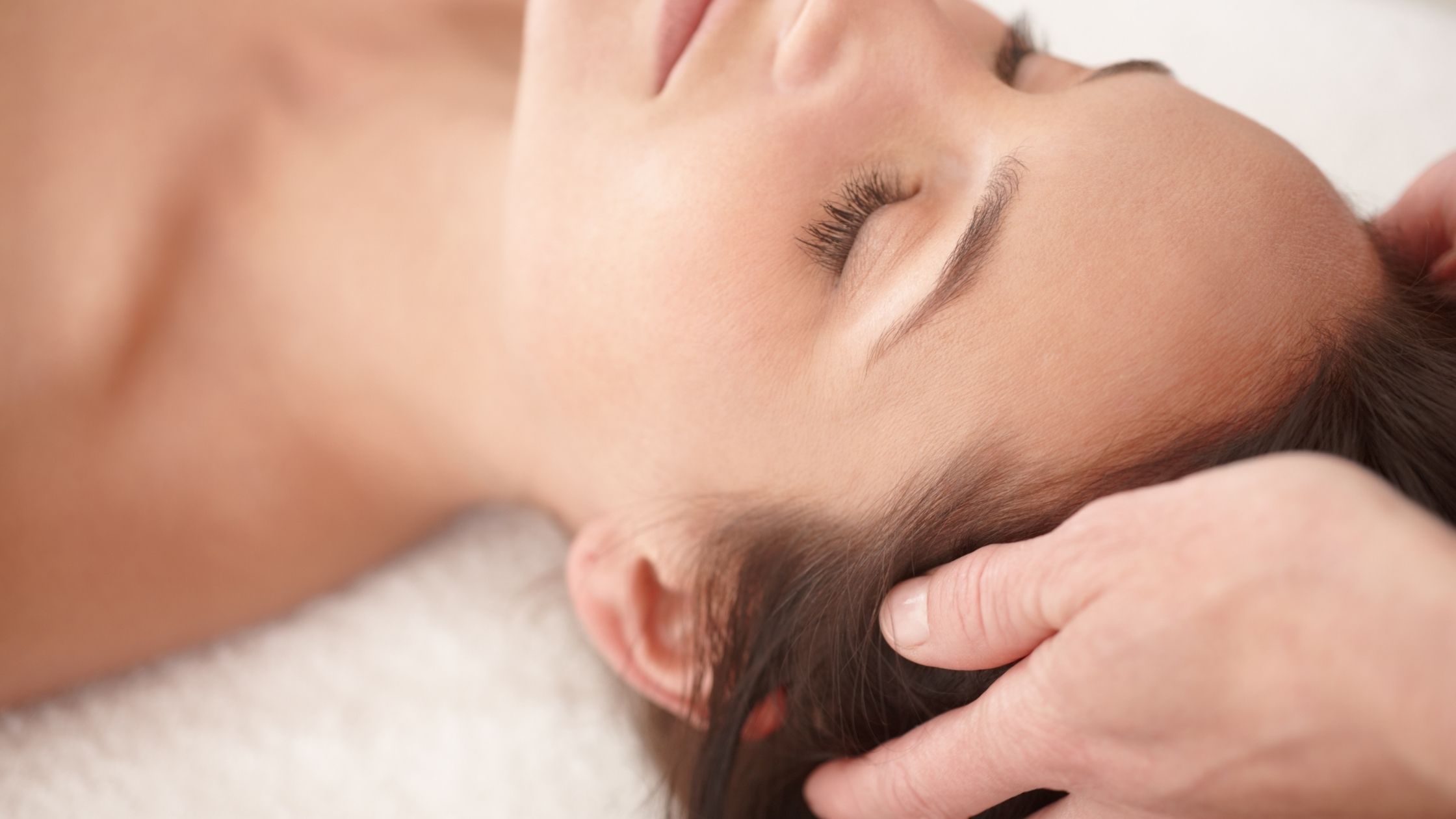 Mujer relajada recibiendo un masaje en la cabeza