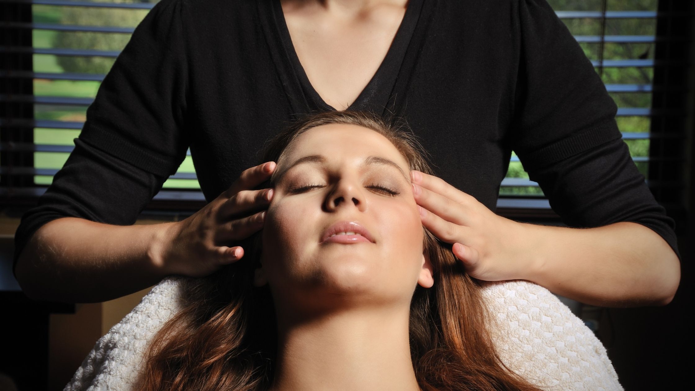 Mujer acostada mientras recibe un masaje en la sien
