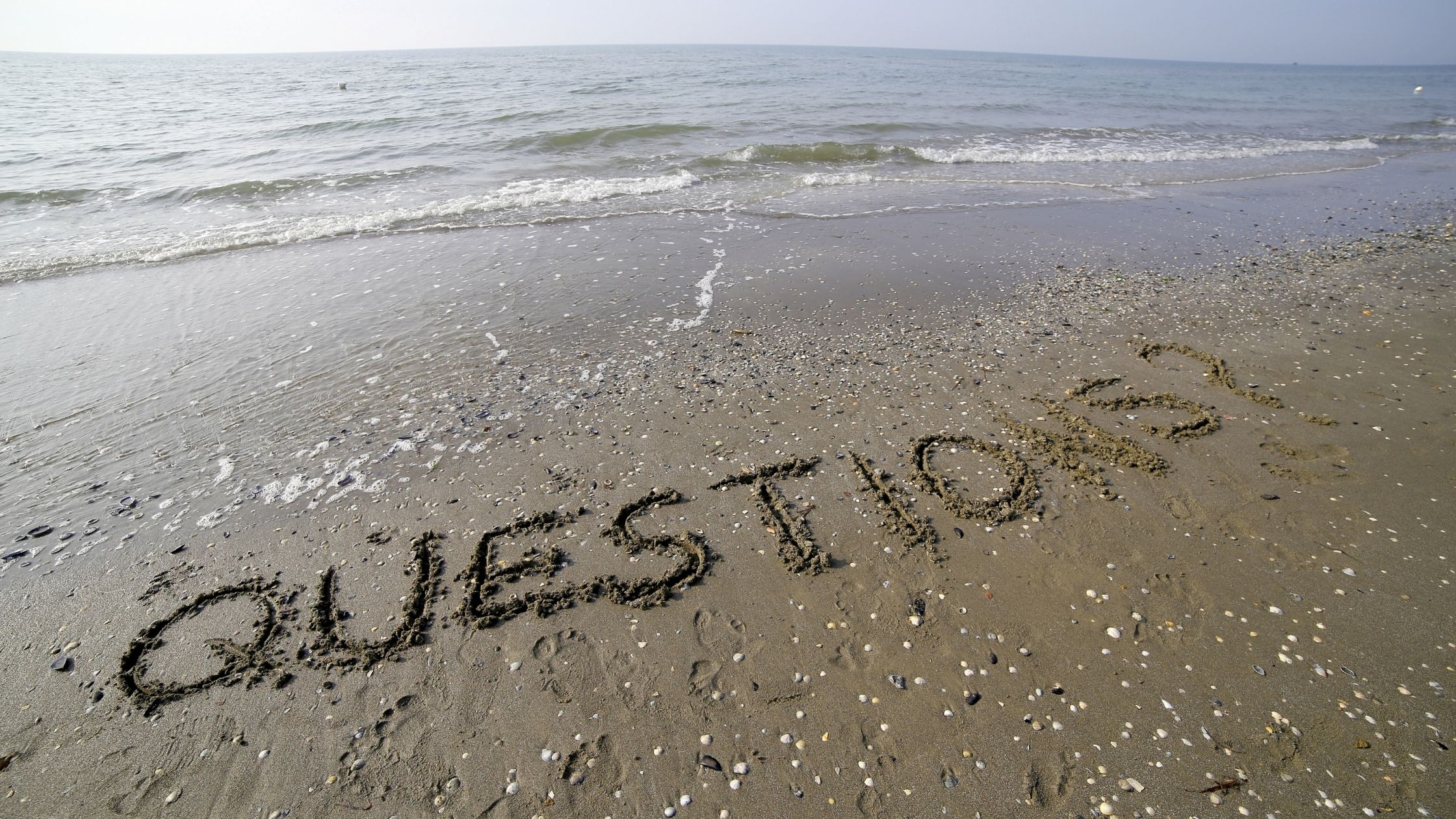 Vista de la playa y en la arena está escrito la palabra Preguntas
