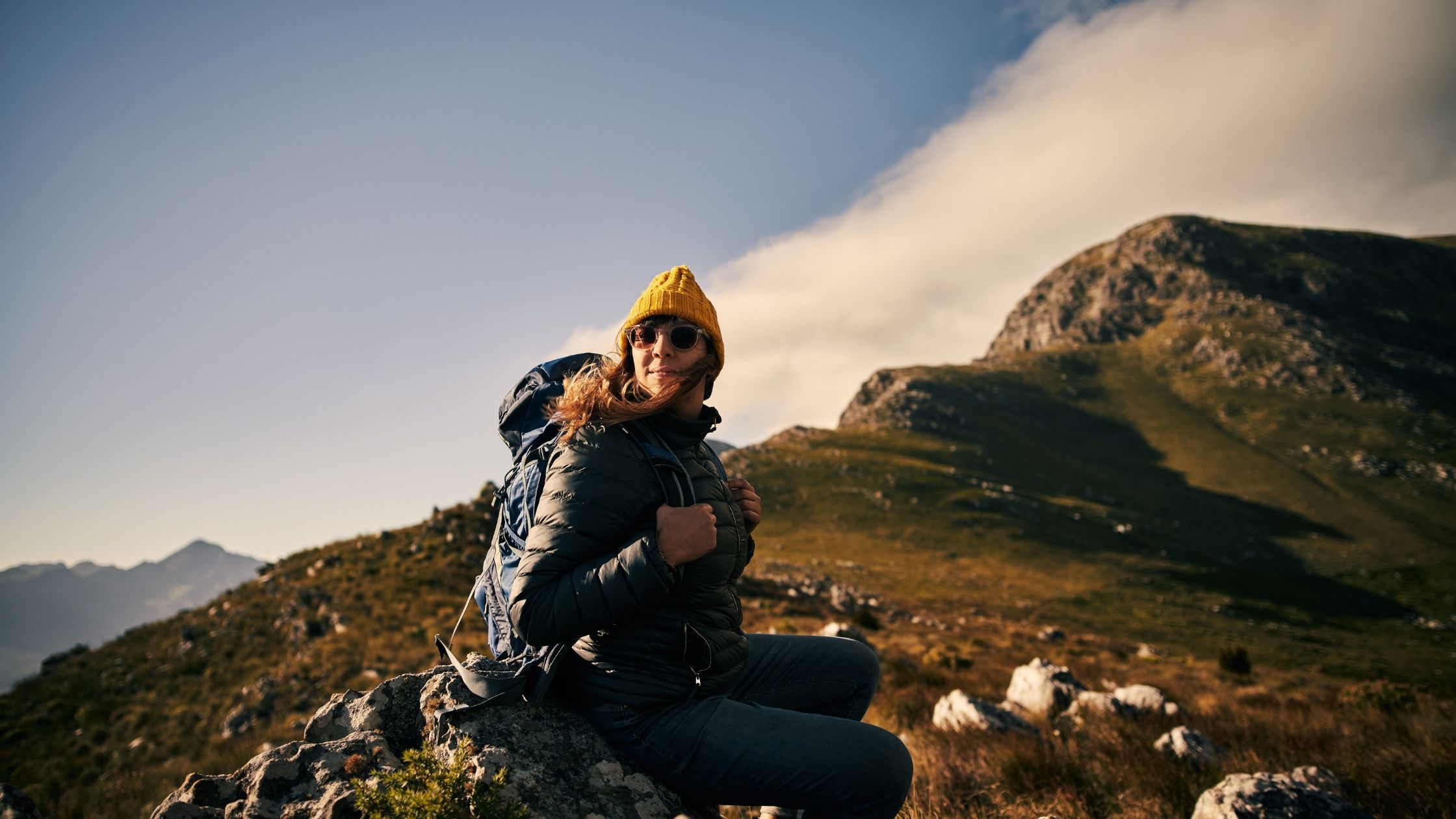 Mujer viajera sentada en una roca y montañas como paisaje de fondo