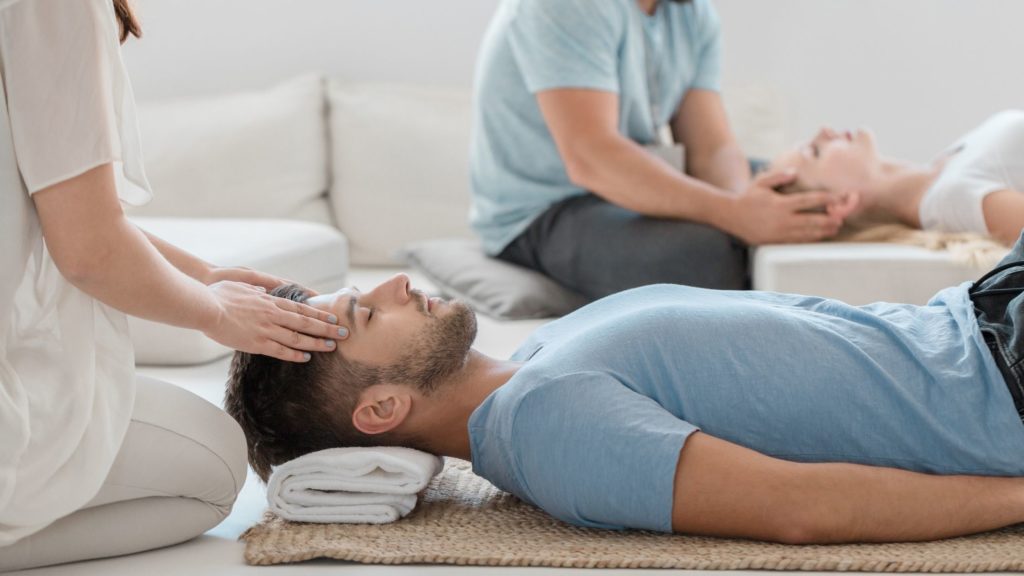 Hombre joven acostado recibiendo un masaje en la parte frontal de la cabeza