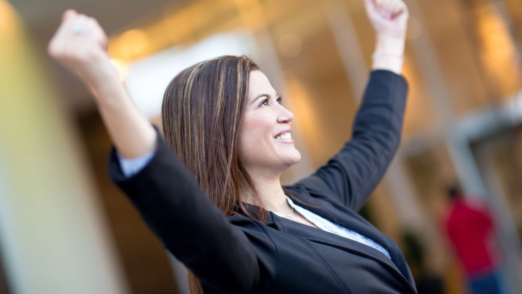 Mujer empresaria con manos al aire en señal de triunfo