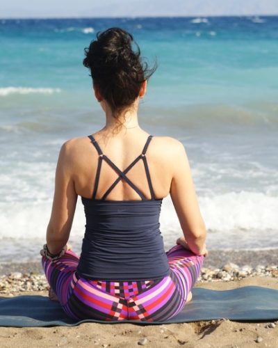 Mujer practicando yoga a orillas de la playa