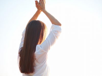 Mujer con manos juntas levantadas en posición de yoga